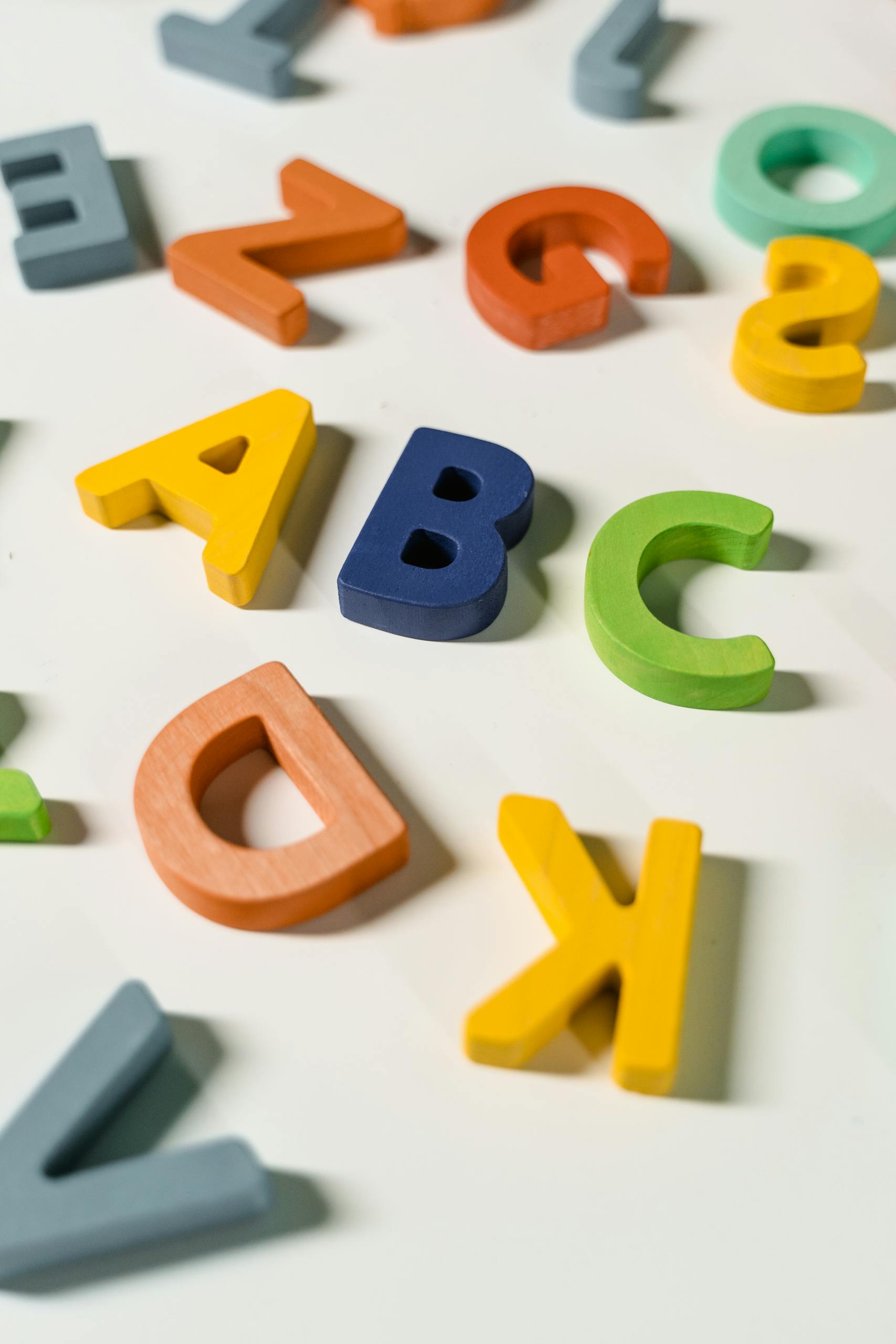Bright and colorful wooden alphabet letters scattered on a white surface. A Child With Dyslexia would have trouble reading.