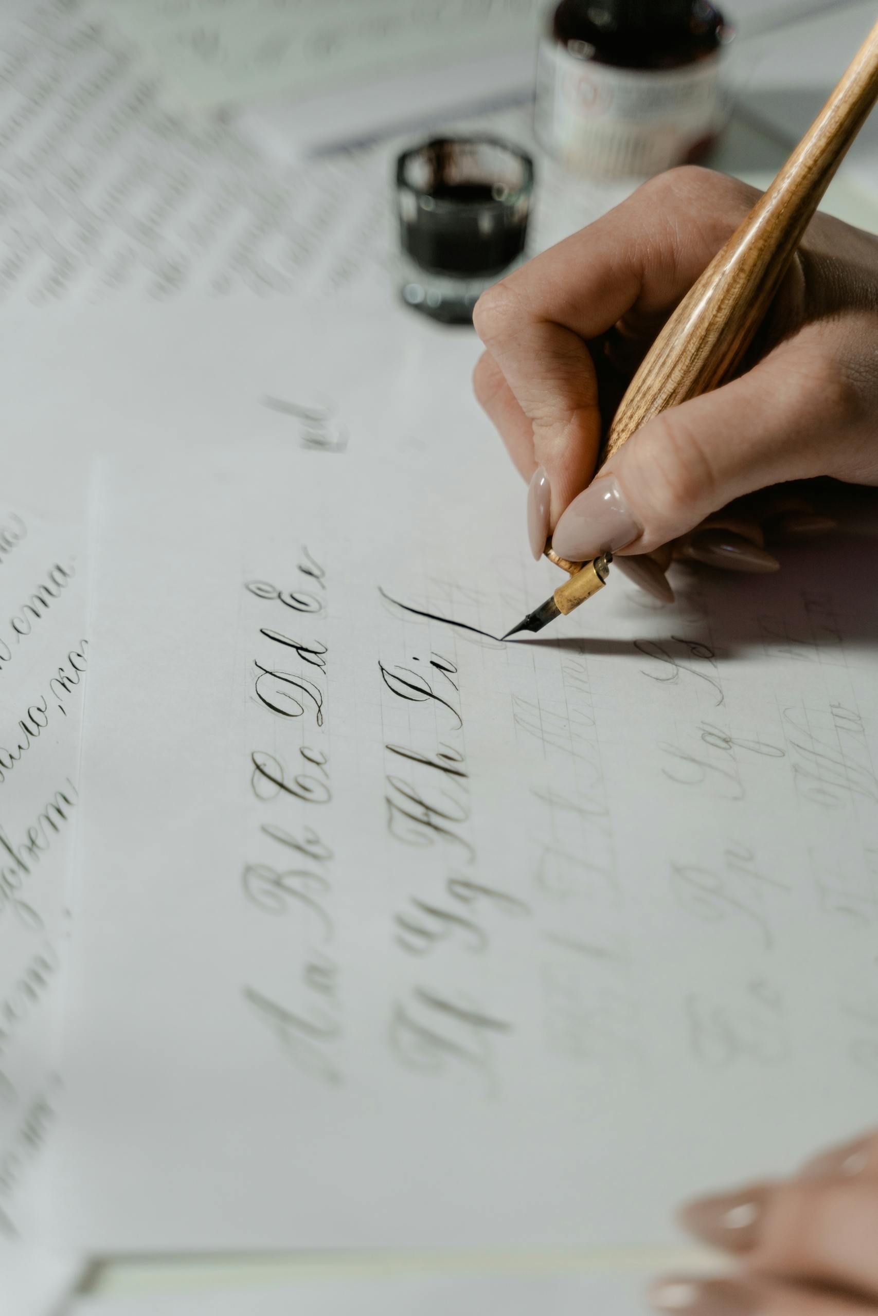 Close-up of practicing elegant calligraphy with ink pen on paper for blog post titled "Should Children Learn Cursive First?"