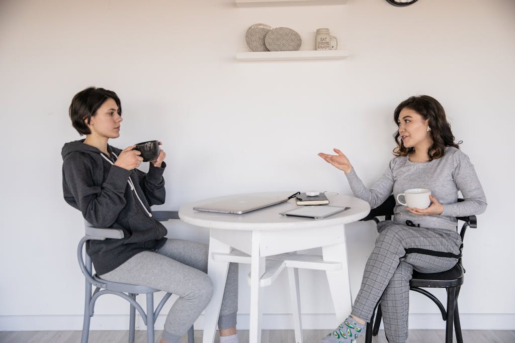 Two women enjoying a casual homeschool conversation with coffee in a cozy indoor setting, enhancing connections.