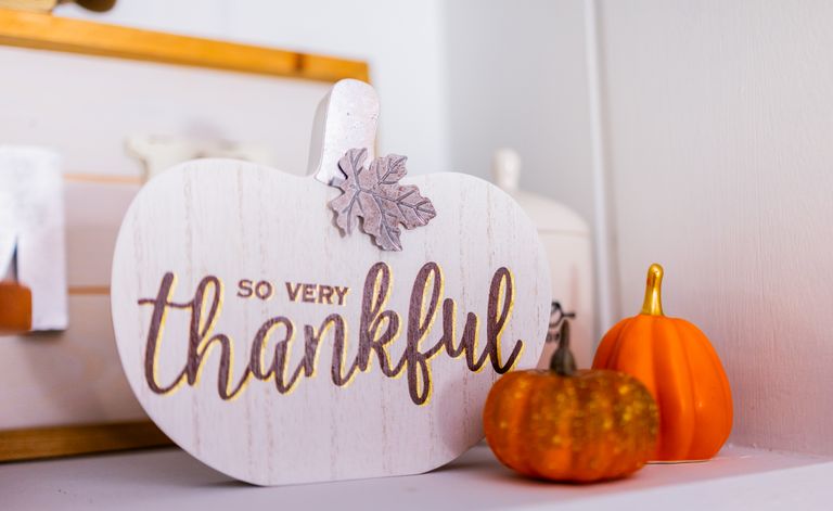 A 'thankful' sign in fall decor featuring small orange pumpkins indoors.